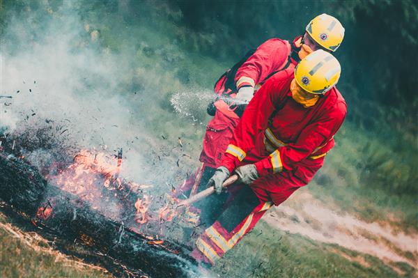 Firefighters extinguish grass fire with beaters and water