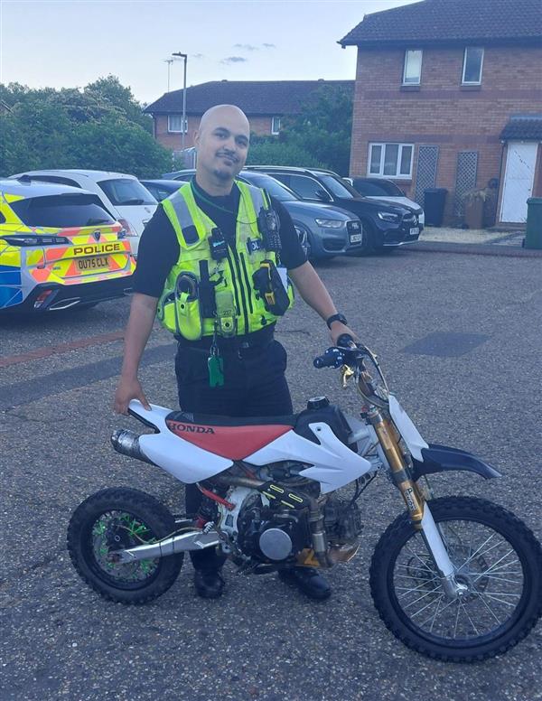 A police officer standing with an off-road motorbike