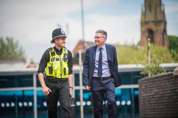 The PCC waks with a police officer in West Bromwich town 