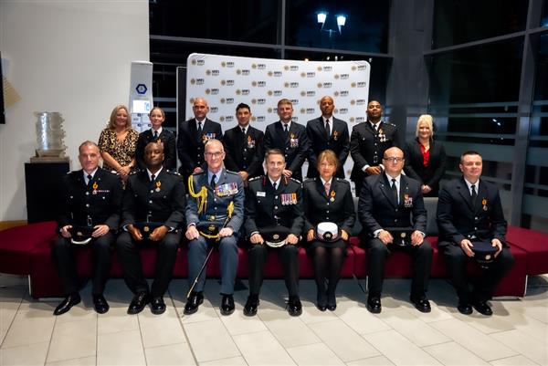 Staff members, some in uniform, sat and stood in two rows together.
