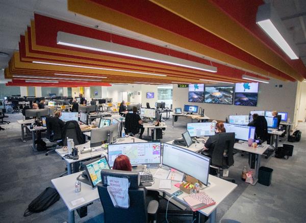 A wide shot photo of Staffordshire and West Midlands Fire Control, showing banks of desks with monitors and Fire Control staff busy working.