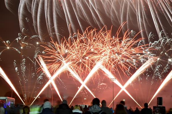 Photo of a range of fireworks at a show, with a crowd in the foreground watching.