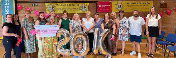 Image shows members of the group posing with a large cheque for for 20K