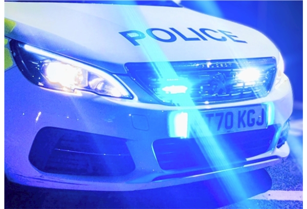 GMP liveried Peugeot 308 police car in the dark with blue lights and headlamps illuminated.