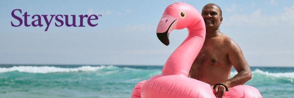 Image shows a man by the sea wearing a flamingo inflatable ring