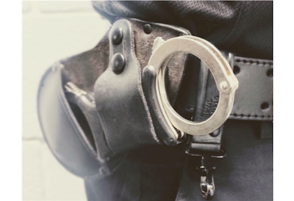 Handcuffs worn on belt in leather holster.