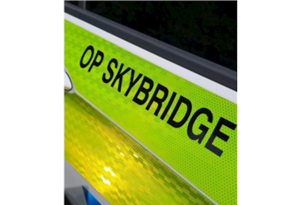 The words "Op Skybridge" written in black font on the side of a police vehicle.