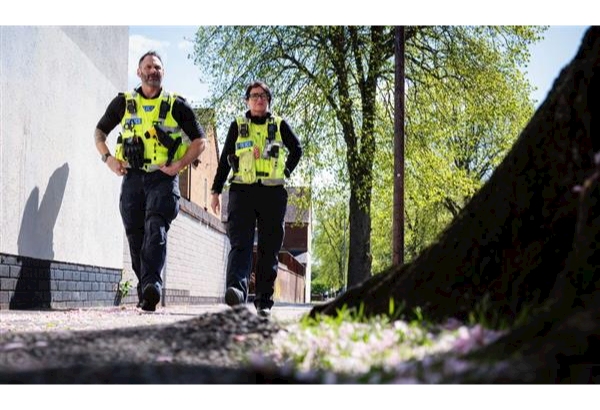 Officers walking beside woodland in sunny weather
