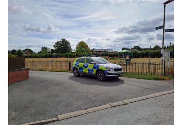 Police car parked in front of playing filed