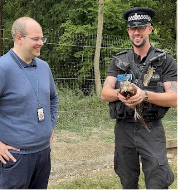 A person in uniform holding a bird

Description automatically generated
