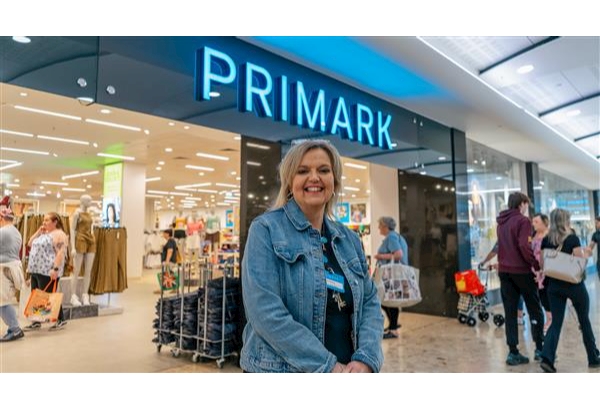 Andrea stood in front of the doorway of Primark Middlesbrough. She is smiling and wearing a blue denim jacket.
