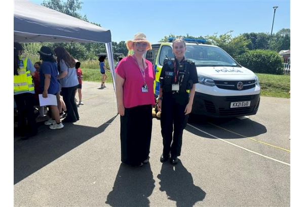 Image of police officer standing next to the headmistress with a police van in the background. 