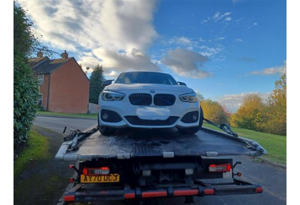 white BMW loaded onto back of recovery vehicle