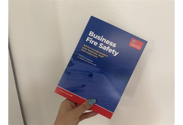 Someone holding a Business Fire Safety booklet filled with leaflets